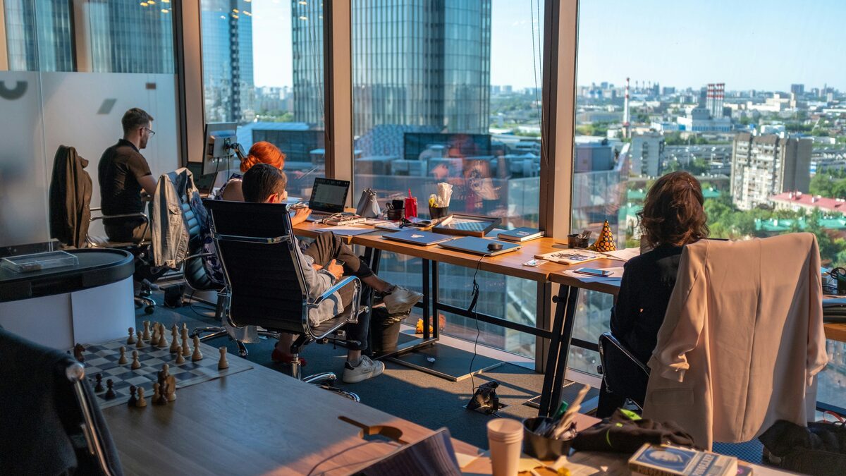Menschen arbeiten an Laptops in einem Büro mit Blick über die Stadt